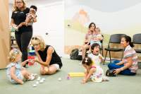 Kids & moms sitting playing by grocery store 